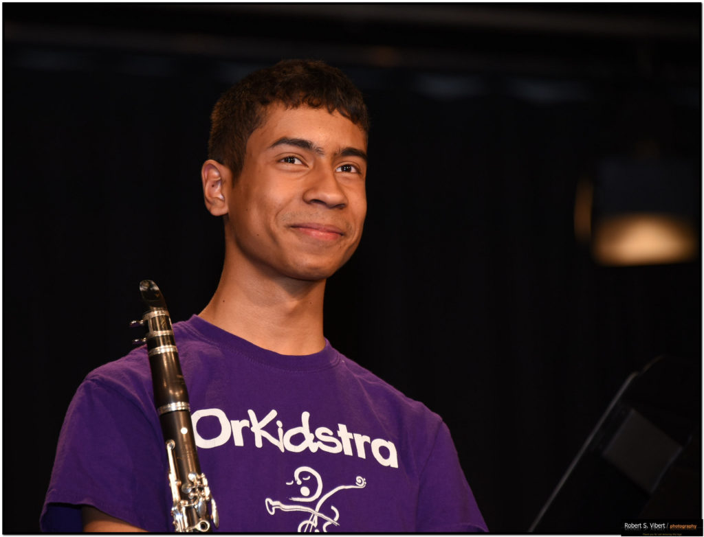 Photo of a young, male OrKidstra student named Peter holding a clarinet and smiling.