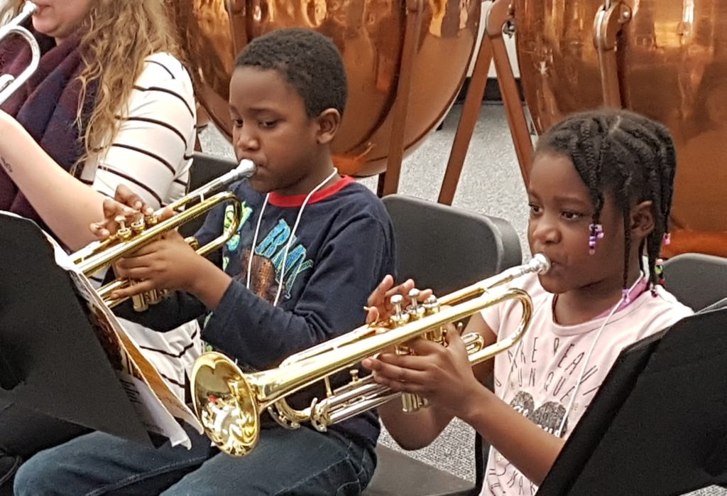 A young girl and boy playing trumpet