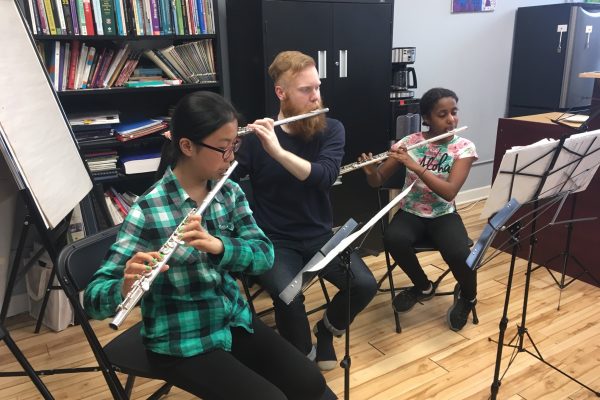 A photo of two young flute students being mentored