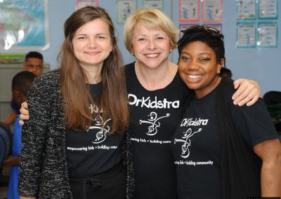 Three women posing with OrKidstra tshirts on