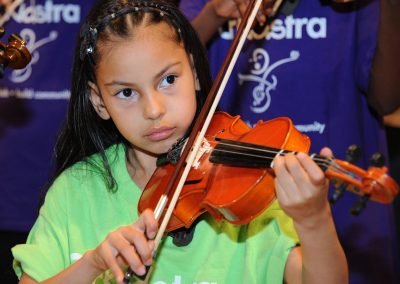 Young girl playing violin in front of group