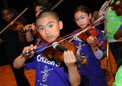 Young boy playing violin in group