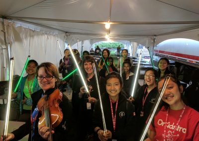A group shot of OrKidstra students holding bows that light up for Canada Day 2017